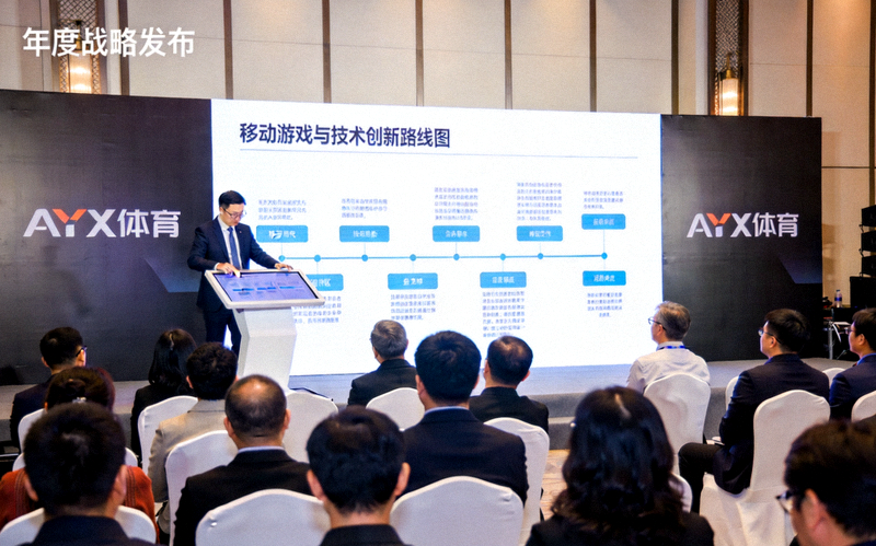 AYX体育年度战略发布会现场：高管在台上使用触摸屏展示移动游戏与技术创新路线图，台下坐满与会者