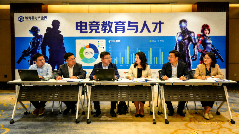 高校电竞发展论坛现场：教育界与产业界代表围坐讨论，背景是‘电竞教育与人才’主题背景板