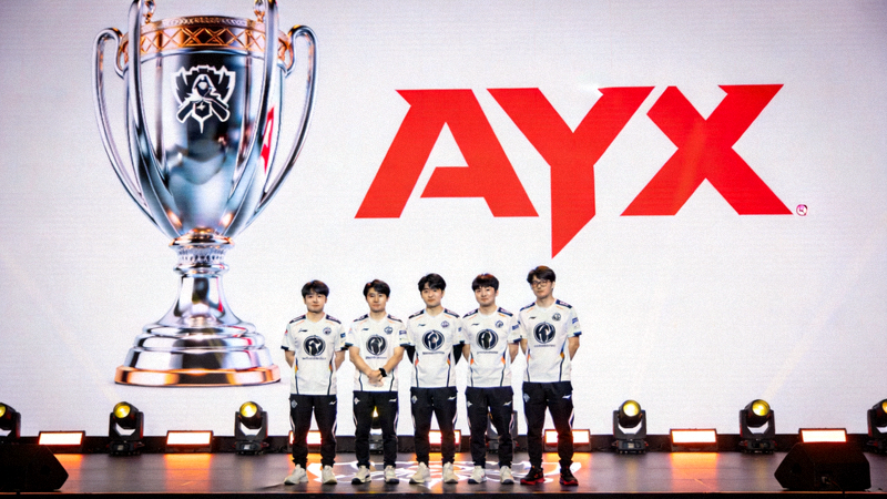 AYX体育签约明星选手发布会现场，五位新签约的电竞选手在舞台上合影，背景是巨大的世界赛奖杯和AYX标志