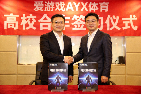 爱游戏AYX体育与高校合作签约仪式，双方代表在电竞教材前握手