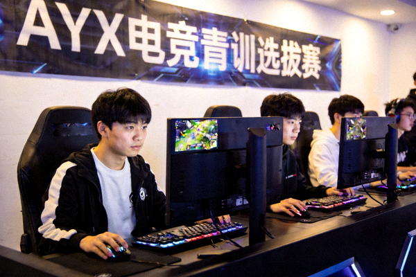 AYX电竞青训选拔赛现场，年轻选手们坐在电脑前全神贯注进行比赛